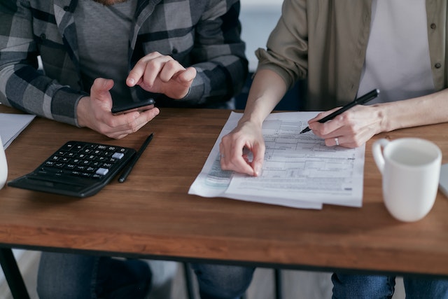 two people with paperwork and a calculator at a table